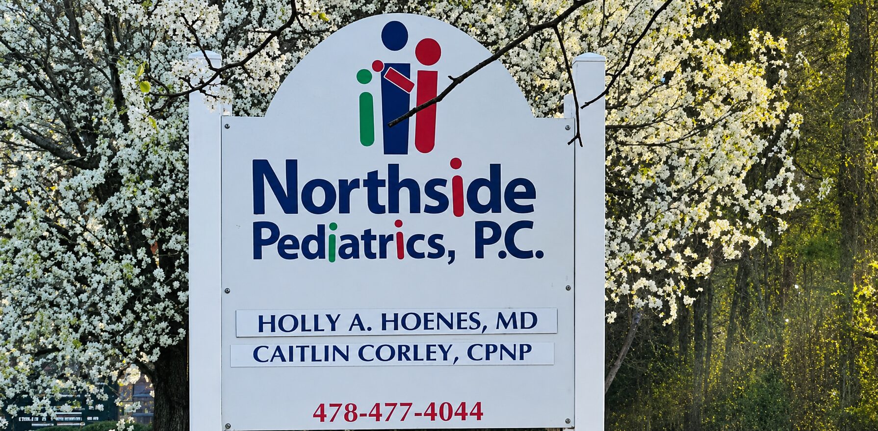 Sign for Northside Pediatrics with blooming trees.
